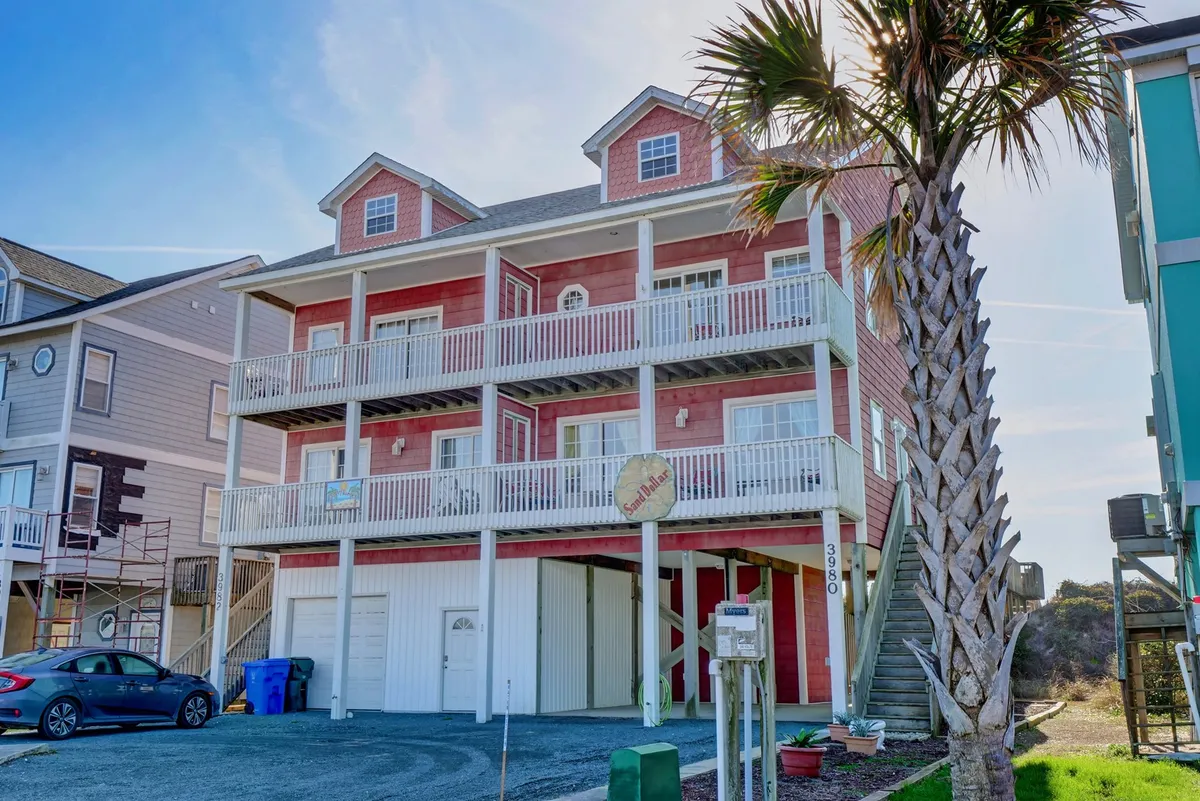 This image shows a cheerful exterior of a colorful duplex with palm trees and multiple balconies. The open balconies offer inviting spaces for groups to relax and enjoy the ocean air, while the vibrant facade sets a lively coastal tone.